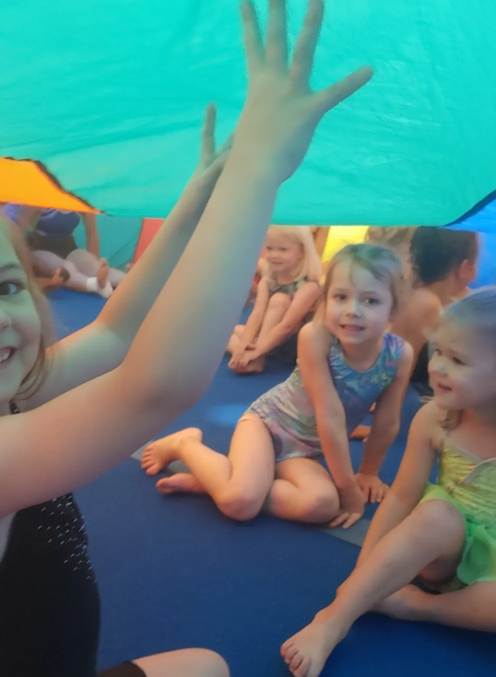 Children playing under a colorful parachute.