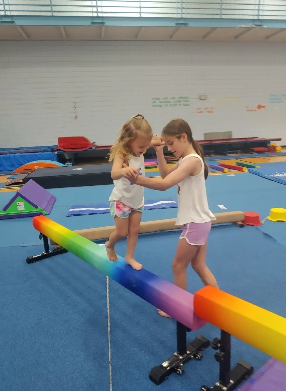 A young gymnast being instructed on a balance beam.
