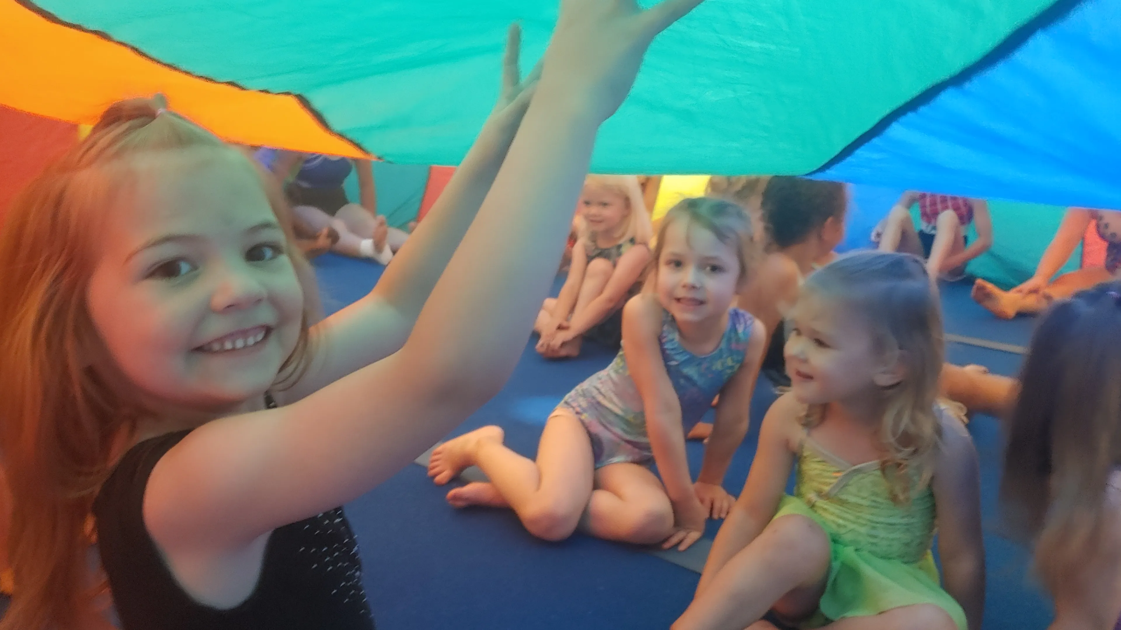 Children playing under a colorful parachute.