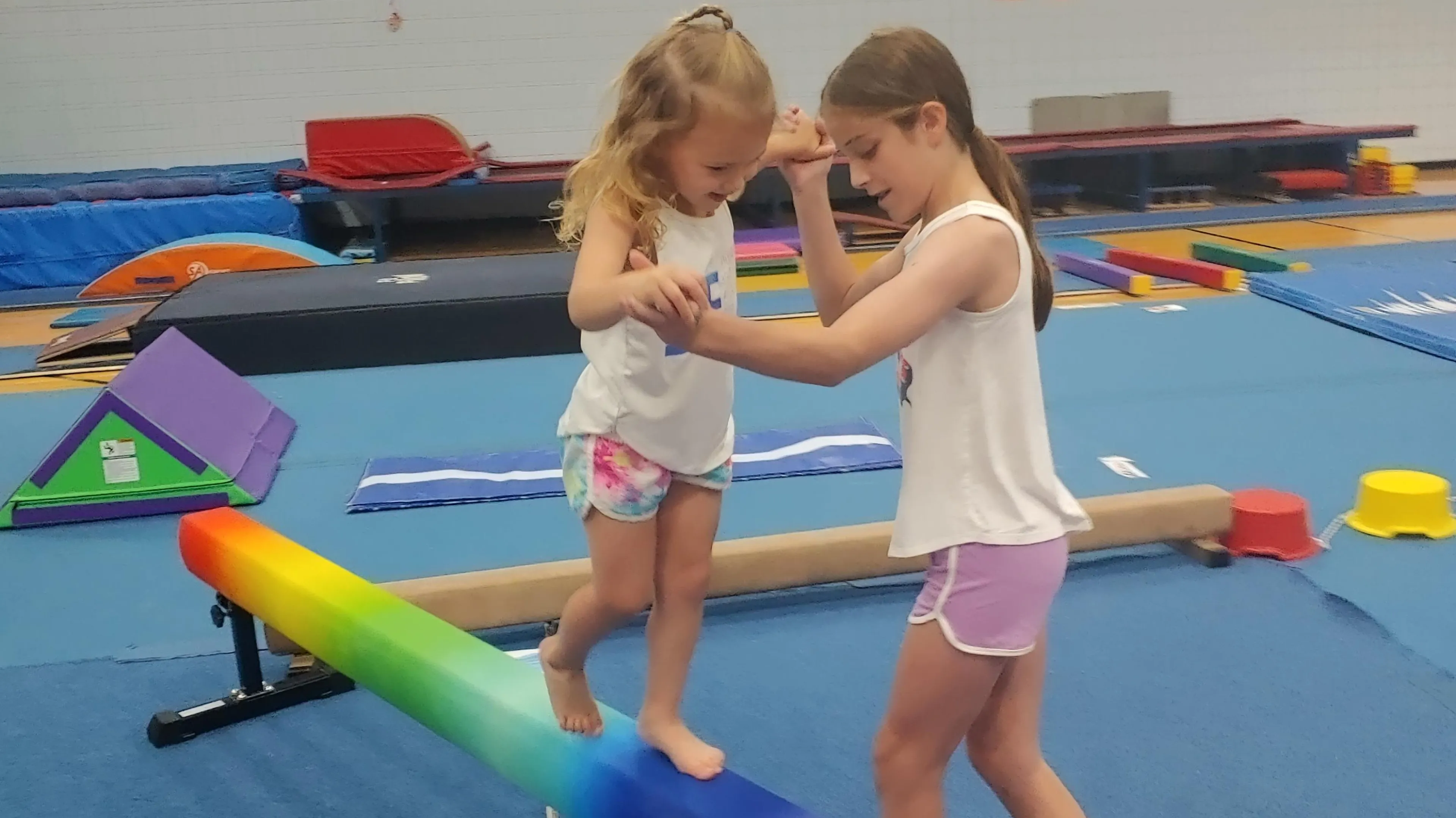 A young gymnast being instructed on a balance beam.