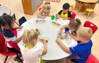 Photo of children at a table doing art projects.
